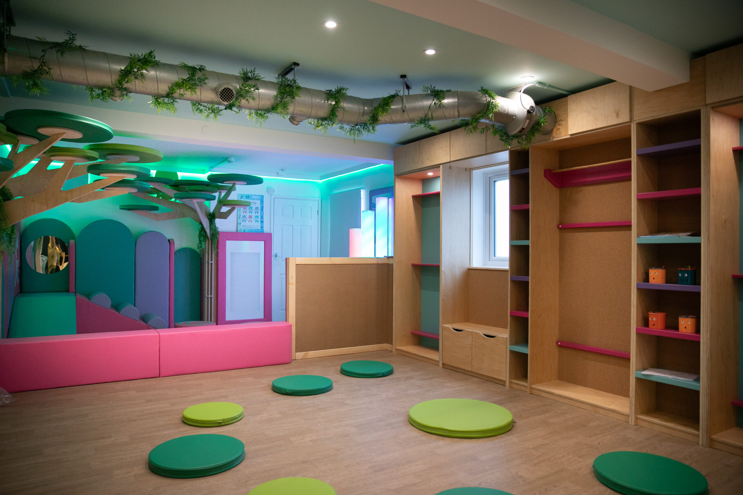 Baby exploring sensory light tubes and textured mats in the baby zone